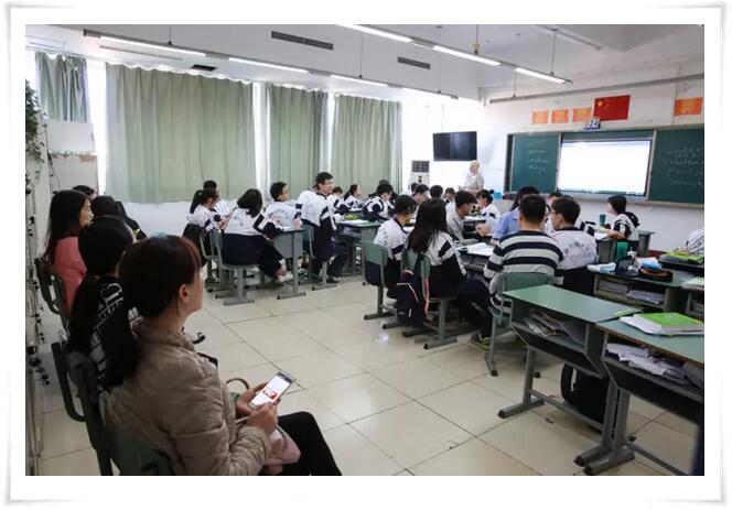 几位家长安静坐在教室后面听课，学生老师也照常上课