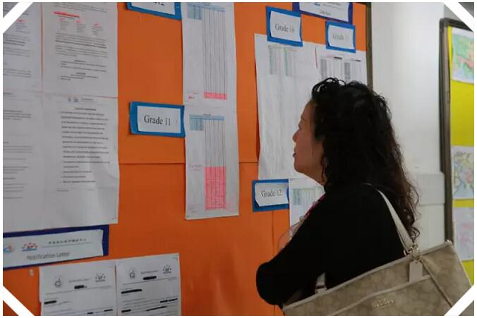 家长在看张贴在过道上的各项成绩与制度